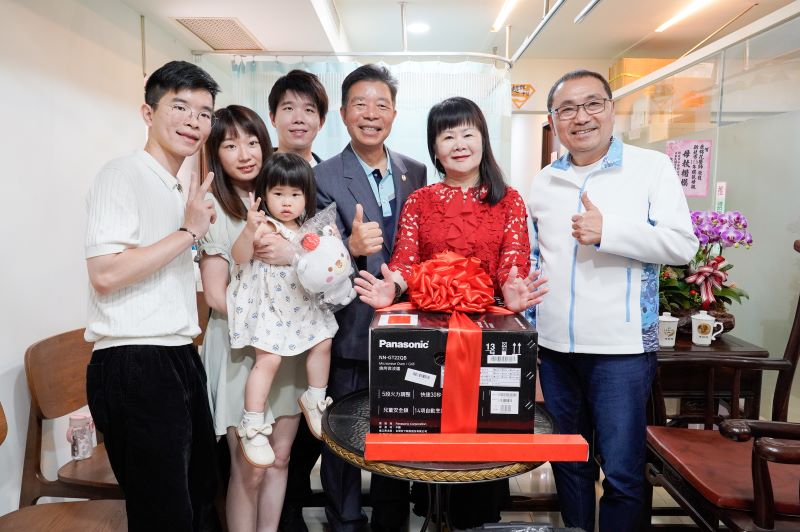 《圖說》侯友宜市長致贈模範母親康錦花燒烤微波爐，並與全家人合影。〈社會局提供〉